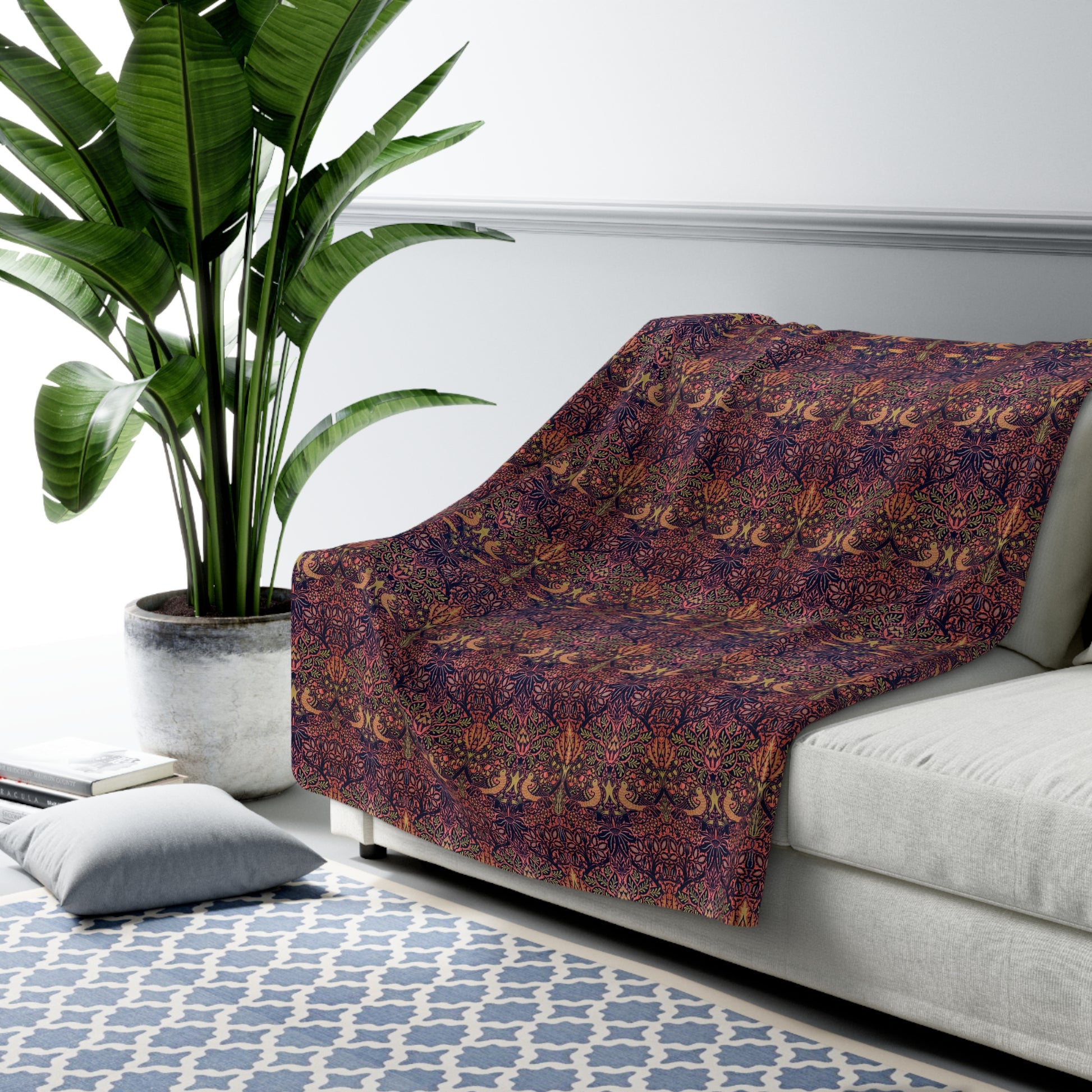 A plush fleece blanket with a floral William Morris & Co pattern in purple, pink and cream colours, folded neatly.