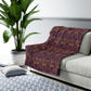A plush fleece blanket with a floral William Morris & Co pattern in purple, pink and cream colours, folded neatly.