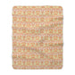 A plush fleece blanket with a geometric pattern in orange and cream colours, laid out flat.