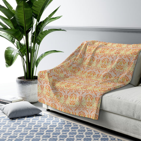 A plush fleece blanket with a geometric pattern in orange and cream colours, laid out flat.