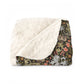 A folded throw blanket featuring a plush cream sherpa fleece backing and a dark green botanical patterned front, displayed on a clean white background.