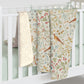 Three patterned baby blankets hanging on a white crib