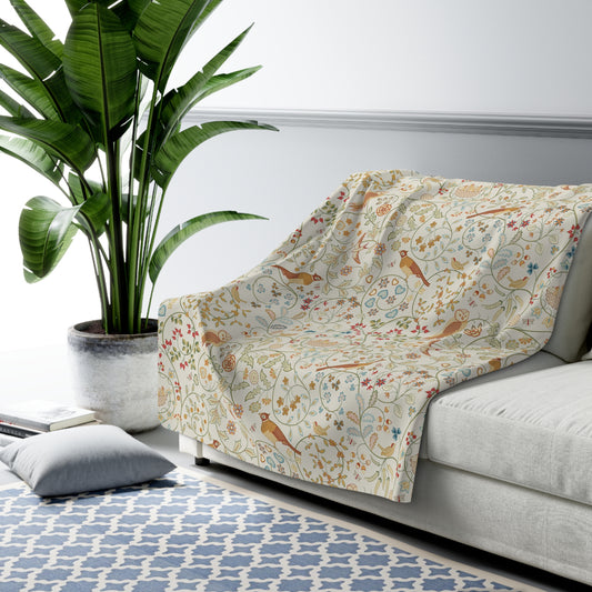 Floral-patterned blanket draped over a sofa in a living room with a plant and rug.