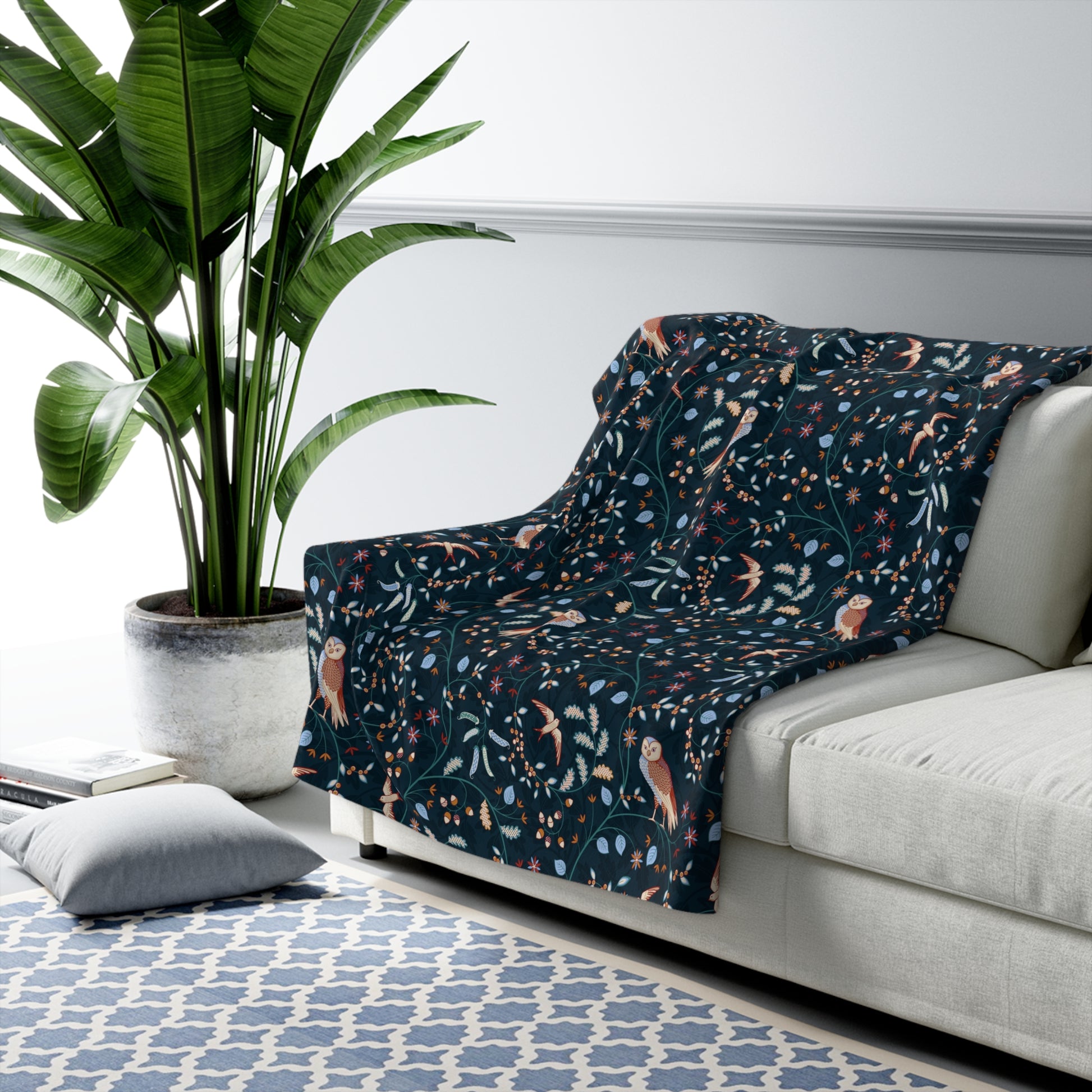 Patterned blanket draped over a sofa in a living room with a plant and rug.