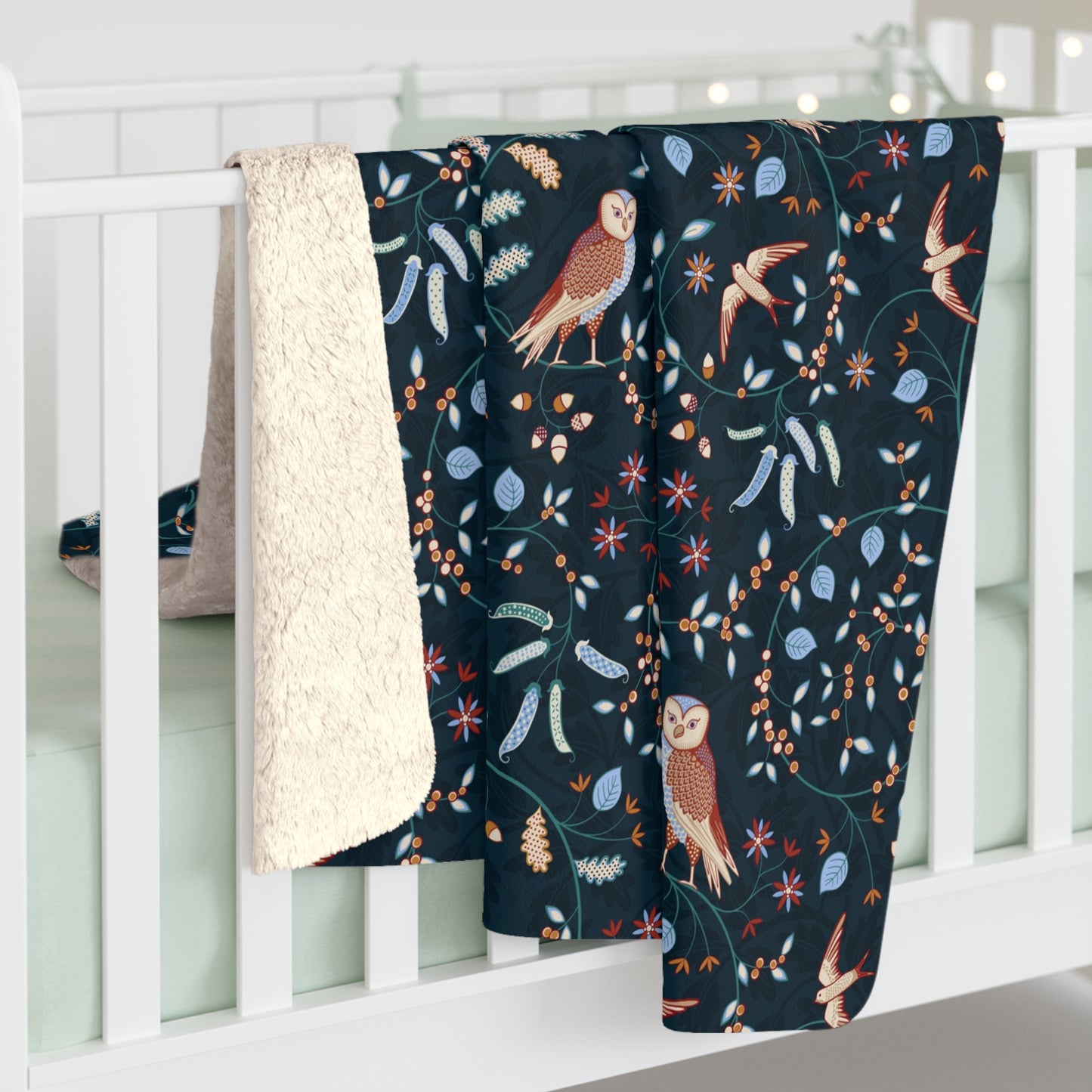 Navy blanket with bird and floral pattern draped over a white crib