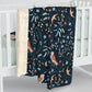 Floral and bird patterned blanket draped over a crib
