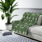 A green Sherpa fleece blanket with a floral pattern inspired by William Morris.