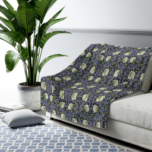 A cozy fluffy fleece blanket with a floral William Morris & Co pattern in shades of purple and green, bound by a solid purple edge.