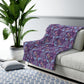 A rectangular Sherpa fleece blanket with a floral William Morris & Co pattern in pink and purple colours.