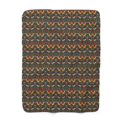 A Sherpa fleece blanket with a geometric William Morris & Co pattern featuring birds and floral-like designs on a dark background.