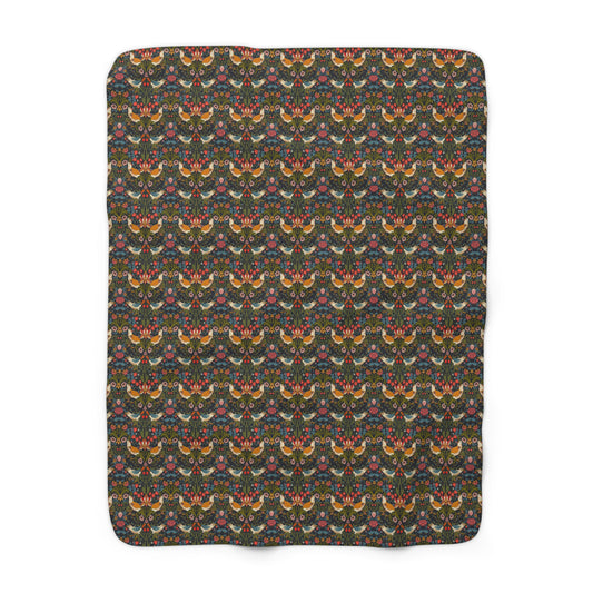 A Sherpa fleece blanket with a geometric William Morris & Co pattern featuring birds and floral-like designs on a dark background.