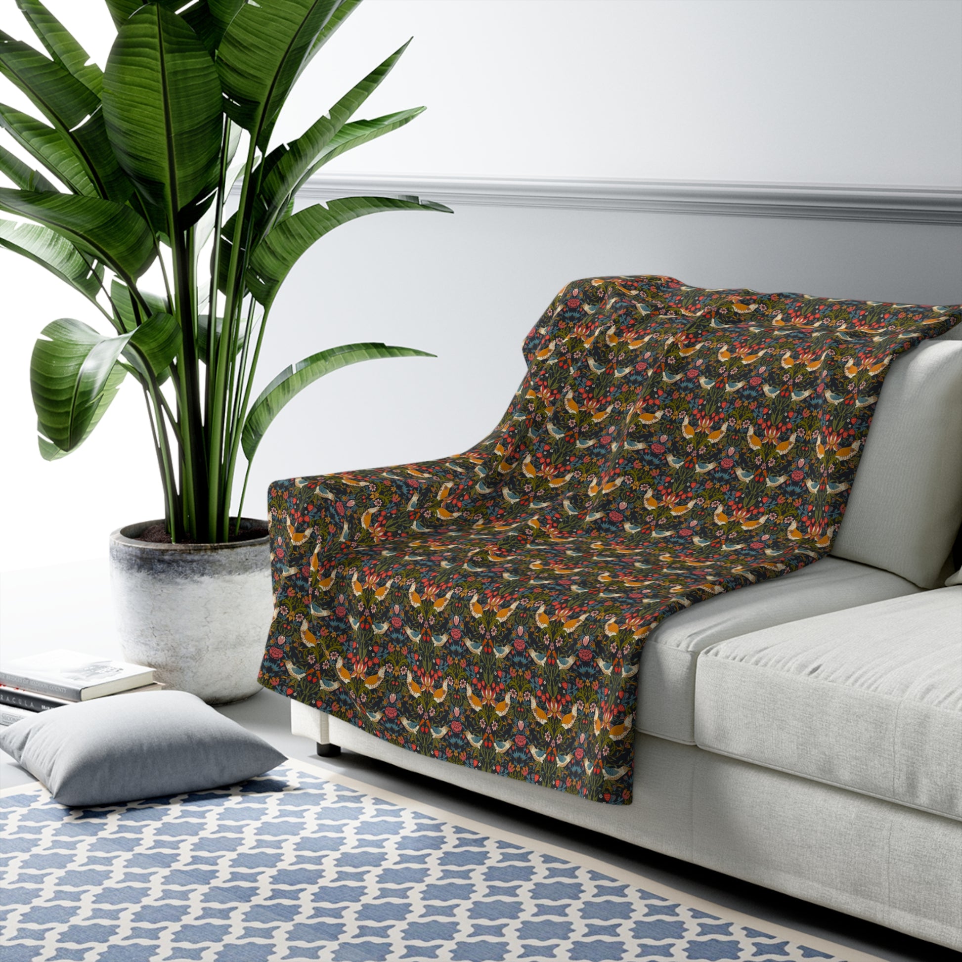 Patterned blanket draped over a sofa in a living room with a plant and rug.