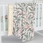 Floral-patterned blanket draped over a crib with a white background