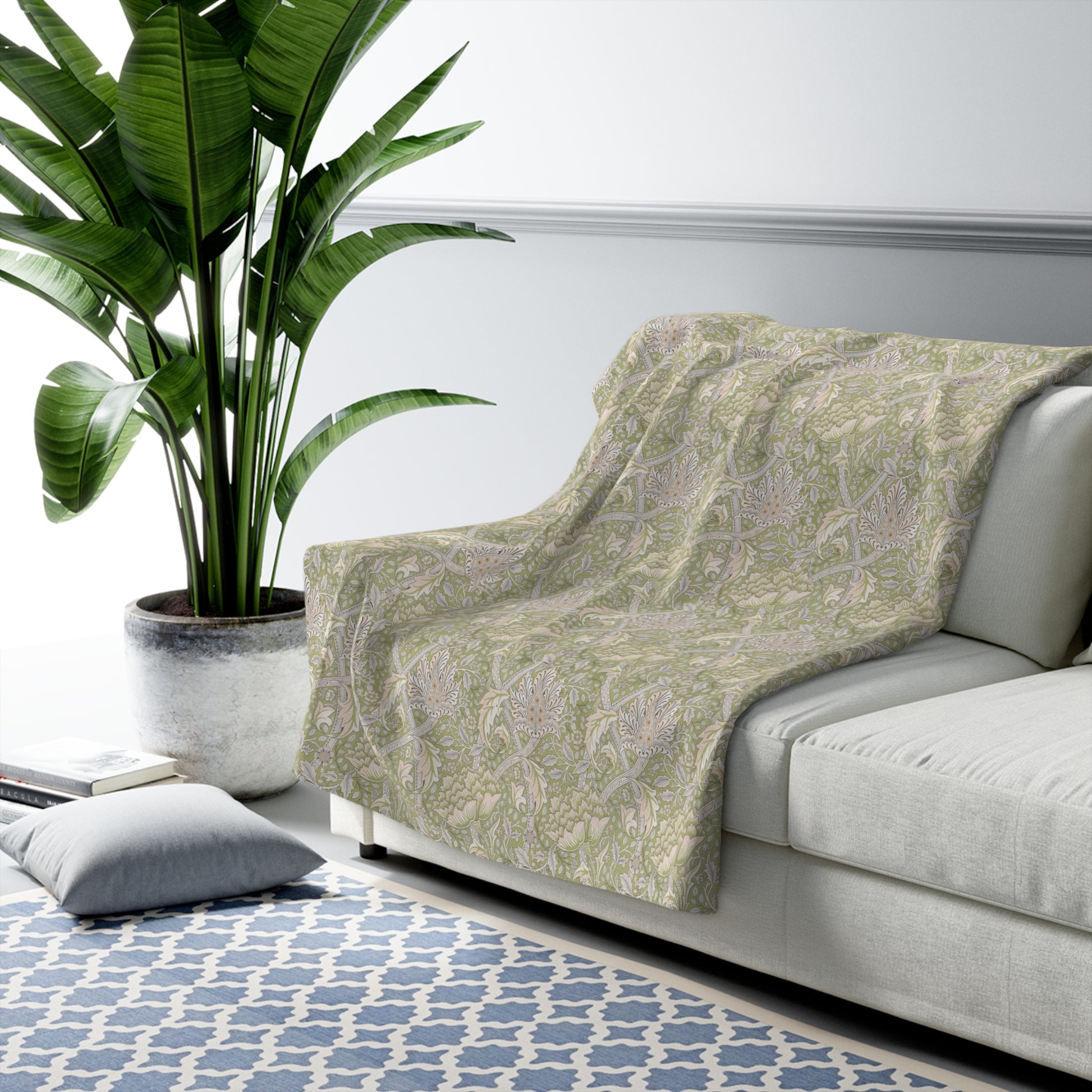 A plush fleece blanket with a floral pattern in green and white tones, inspired by William Morris.