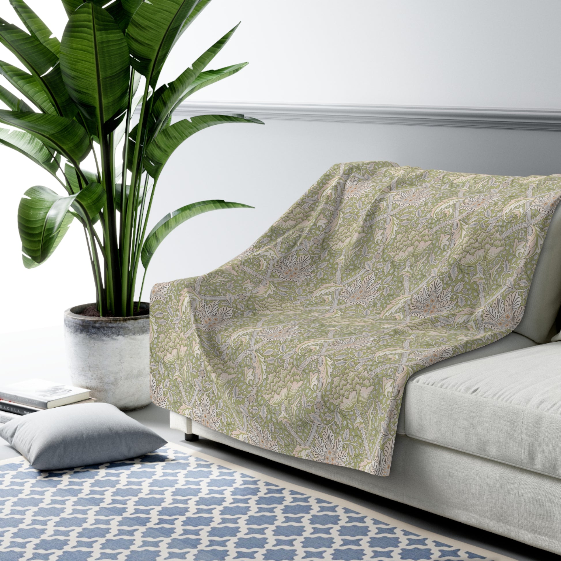 A plush fleece blanket with a floral pattern in green and white tones, inspired by William Morris.