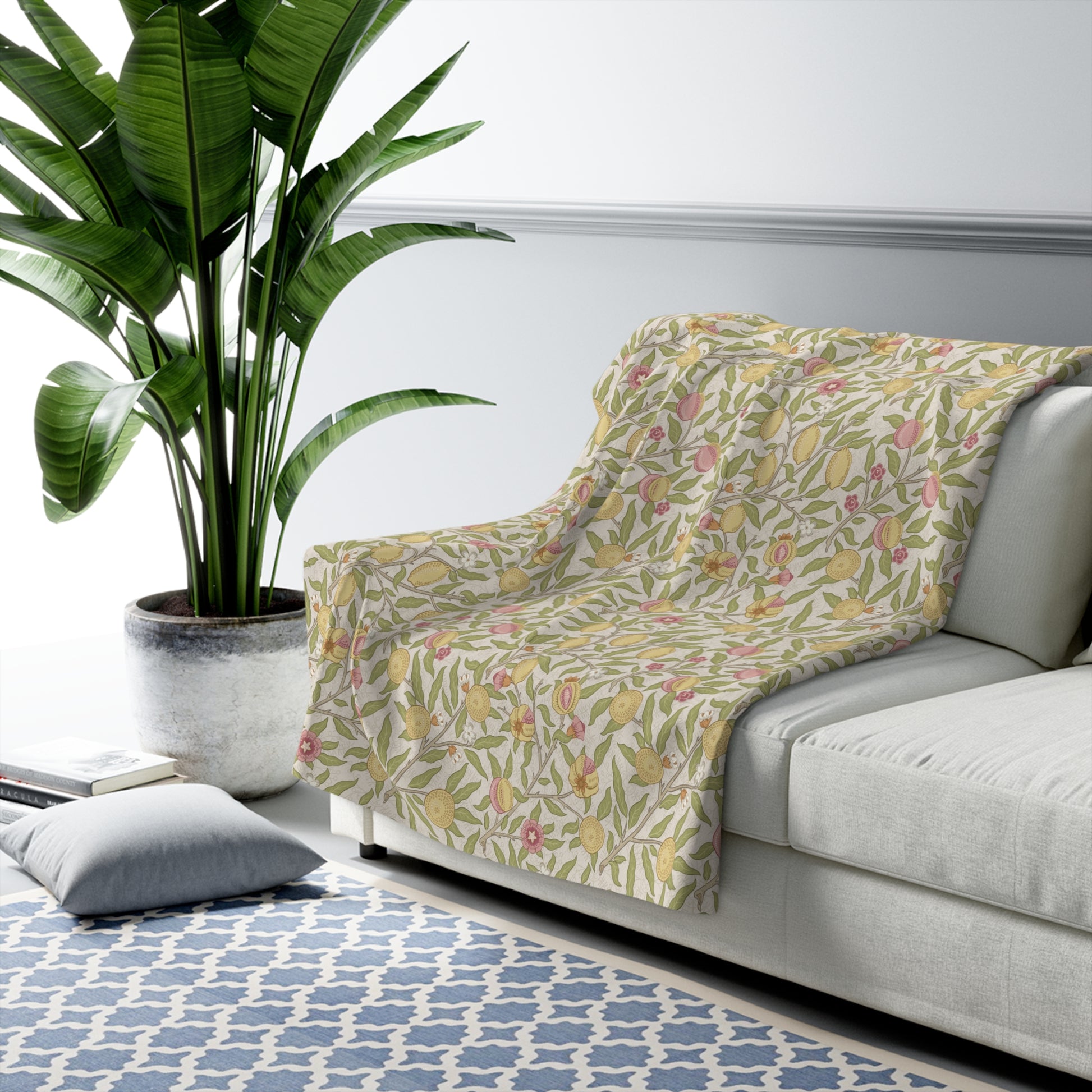 Floral-patterned blanket draped over a sofa in a living room with a plant and rug.