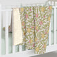 Floral-patterned baby blankets hanging on a white crib