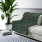 A Sherpa fleece blanket with a floral pattern in green and brown tones, underside showing plush cream sherpa fleece.