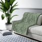 A green Sherpa fleece blanket with a floral pattern inspired by William Morris, displayed flat.