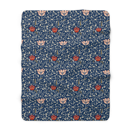 A navy blue Sherpa fleece blanket with a floral pattern inspired by William Morris's design.