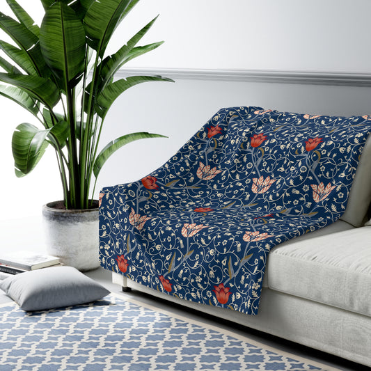 A navy blue Sherpa fleece blanket with a floral pattern inspired by William Morris's design.