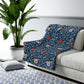 A navy blue Sherpa fleece blanket with a floral pattern inspired by William Morris's design.