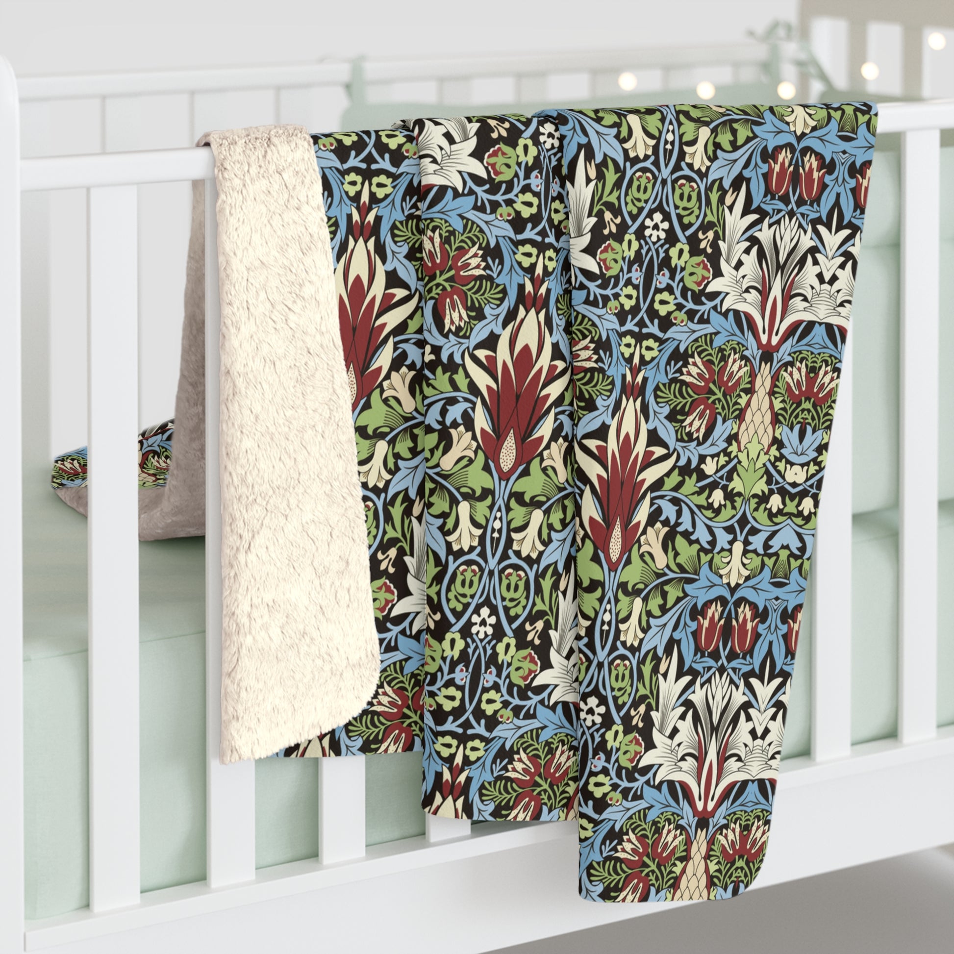 Colourful patterned quilt draped over a white crib from William Morris