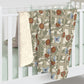 A Sherpa fleece blanket with a floral pattern in beige, green, blue, and red colours on a white background.