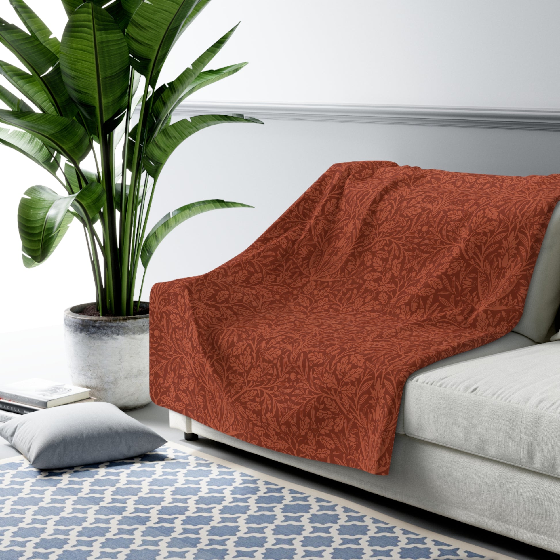 A rectangular Sherpa fleece blanket with a rust-coloured floral pattern inspired by William Morris & Co - Acorns and Oak Trees Collection.