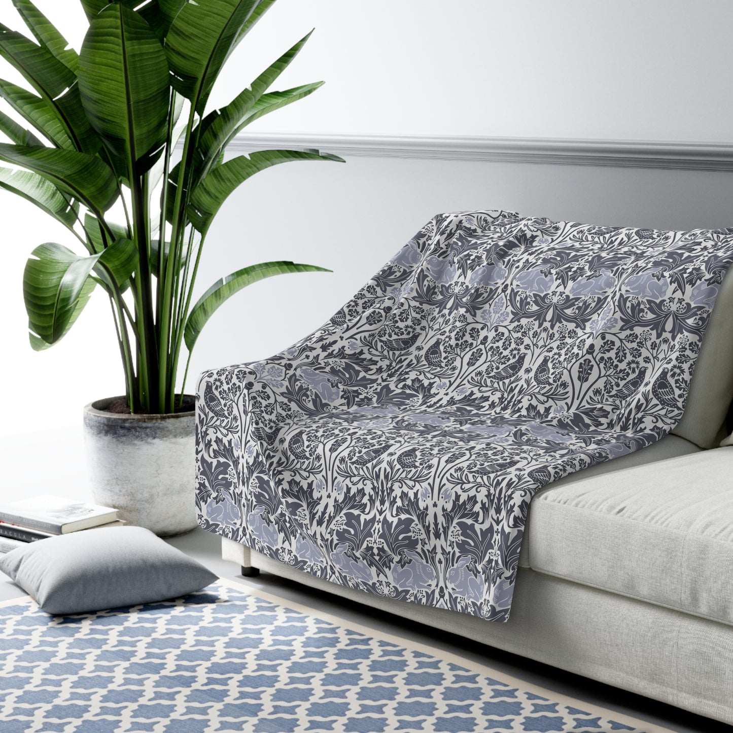 A grey Sherpa fleece blanket with a floral pattern, inspired by William Morris, from the Brer Rabbit collection.