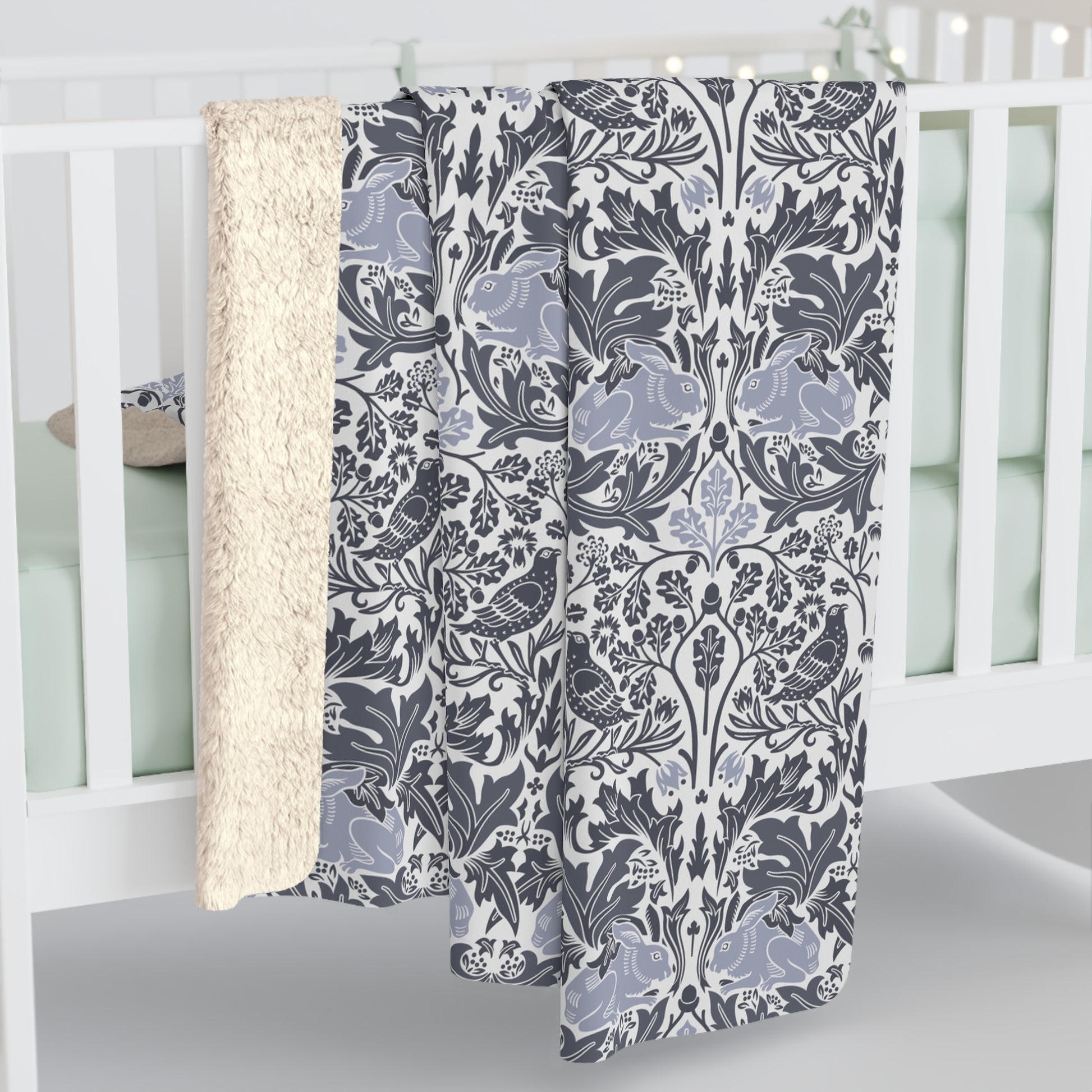 A grey Sherpa fleece blanket with a floral pattern, inspired by William Morris, from the Brer Rabbit collection.