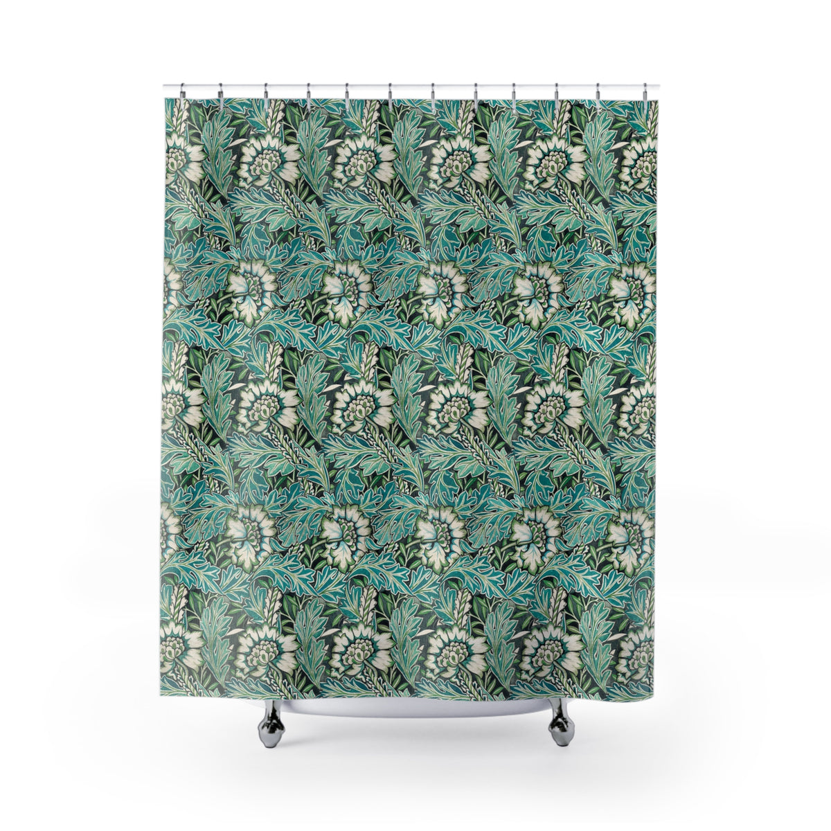 A bathroom scene showing a shower curtain with a teal, green, and white botanical leaf pattern hanging in a shower. The bathroom also features a white vanity with a marble countertop, a mirror, and a blue-gray accent wall.