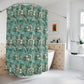A bathroom scene showing a shower curtain with a teal, green, and white botanical leaf pattern hanging in a shower. The bathroom also features a white vanity with a marble countertop, a mirror, and a blue-gray accent wall.