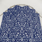 Blue fabric with white floral pattern draped over a circular metal stand on a white background
