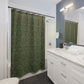 Bathroom with green patterned shower curtain, white vanity, and mirror.