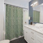 Bathroom with green patterned shower curtain, white vanity, and mirror.