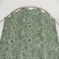 Green floral patterned fabric on a hanger against a white background