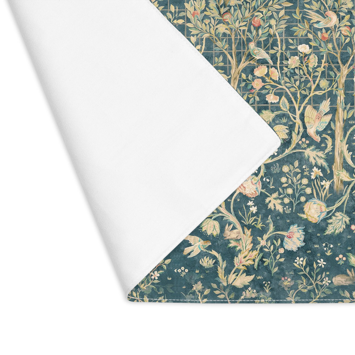 A folded cloth placemat with a classic botanical and bird pattern, showing the white reverse side against a clean white background.