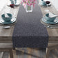 A smoky blue table runner with a leaf pattern displayed on a dining table.