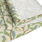 A table runner with a Victorian William Morris & Co floral design in green, blue, and brown colours, laid out on a dining table.