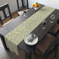 A table runner with a Victorian William Morris & Co floral design in green, blue, and brown colours, laid out on a dining table.
