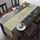 A table runner with a Victorian William Morris & Co floral design in green, blue, and brown colours, laid out on a dining table.