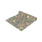 A table runner with a William Morris & Co Victorian-inspired bird and pomegranate pattern laid out on a dining table.