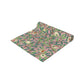 A table runner with a William Morris & Co Victorian-inspired bird and pomegranate pattern laid out on a dining table.
