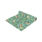 A tiffany blue table runner with a William Morris & Co floral and bird design laid out on a dining table with dishes and cutlery.