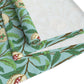 A tiffany blue table runner with a William Morris & Co floral and bird design laid out on a dining table with dishes and cutlery.
