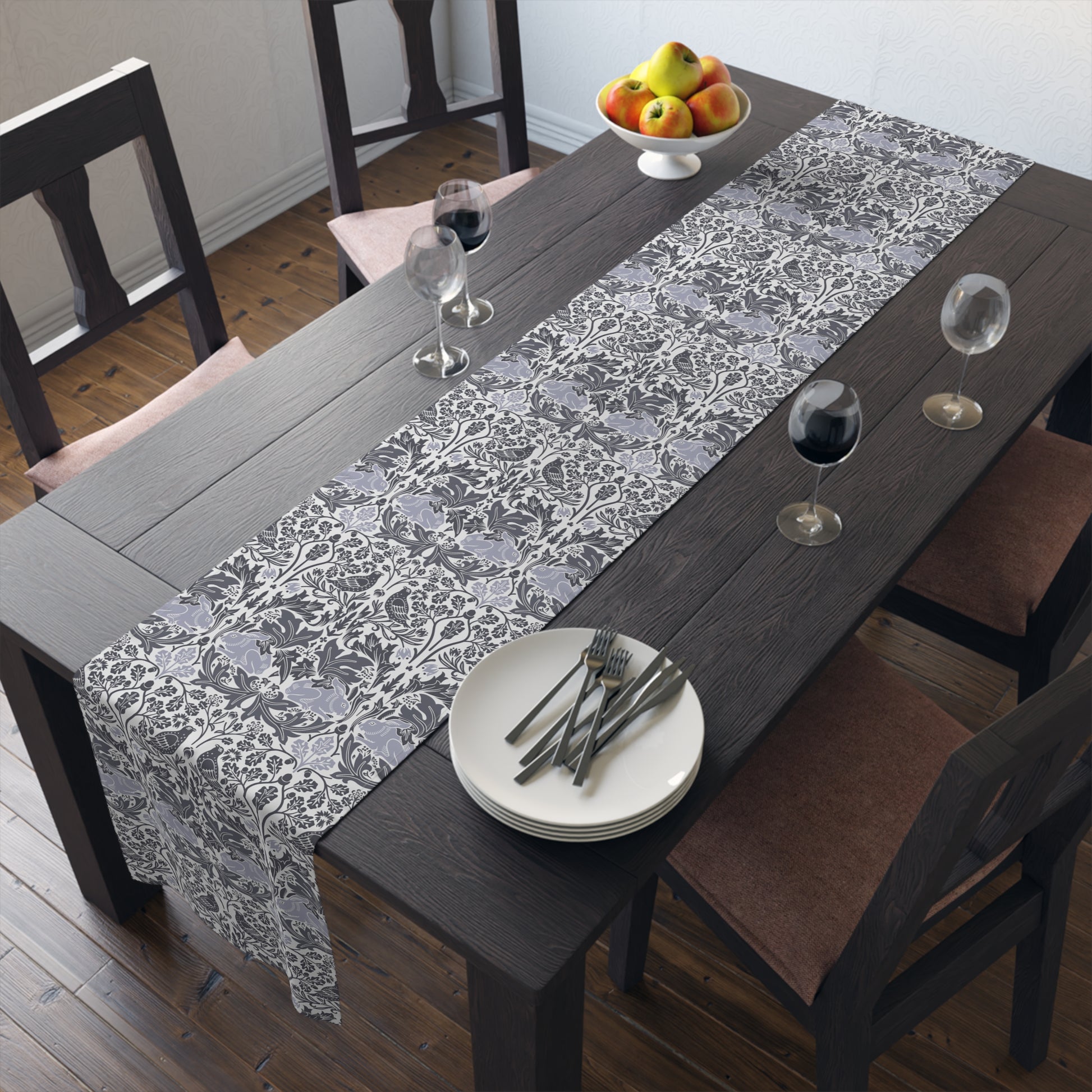 Dining table with a floral runner, plates, and glasses in a home setting.
