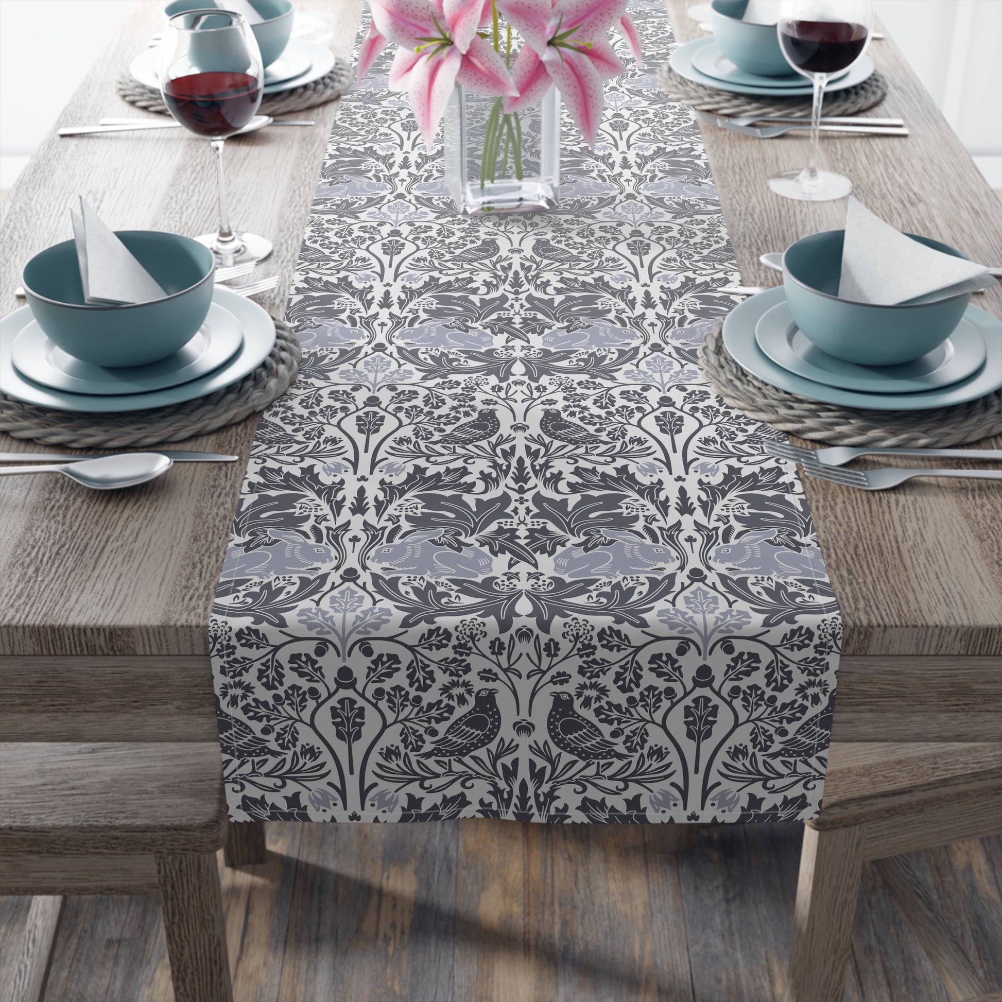 Dining table set with a decorative table runner, bowls, and glasses on a wooden table.