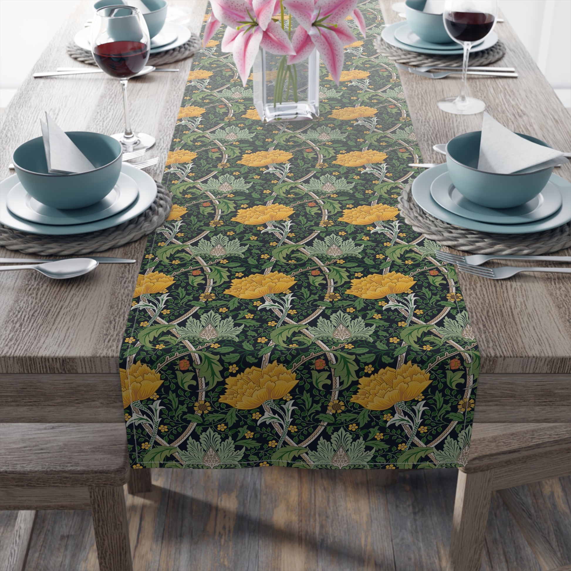A yellow and green floral patterned table runner with hemmed edges displayed on a dining table.