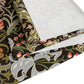 A table runner with a floral William Morris & Co pattern in shades of green, gold, and other colours, laid out on a dining table with dishes and glasses arranged on top.